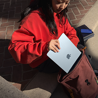 A student placing a 15" MacBook Air into their backpack